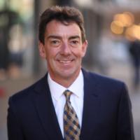 A person in a suit and tie smiling on a city street.